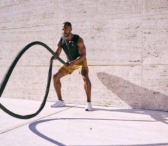 Very muscular man wearing Aion men's weighted vest while throwing weighted rope