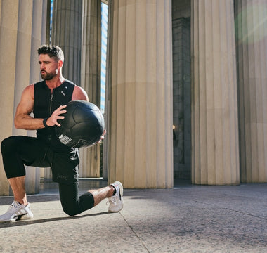 fit man doing walking lunges with a large weighted medicine ball wearing the Aion men's weighted vest