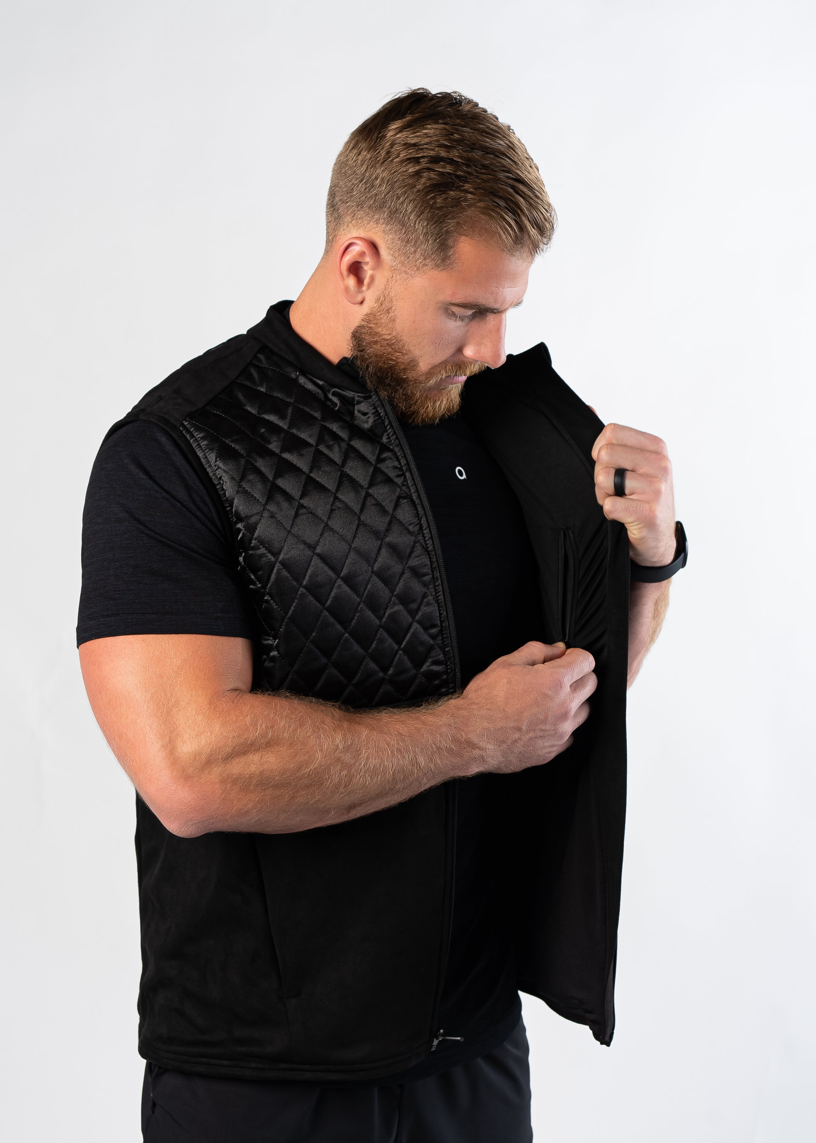 Man examining interior pockets of Aion Boardroom Recovery Vest in black