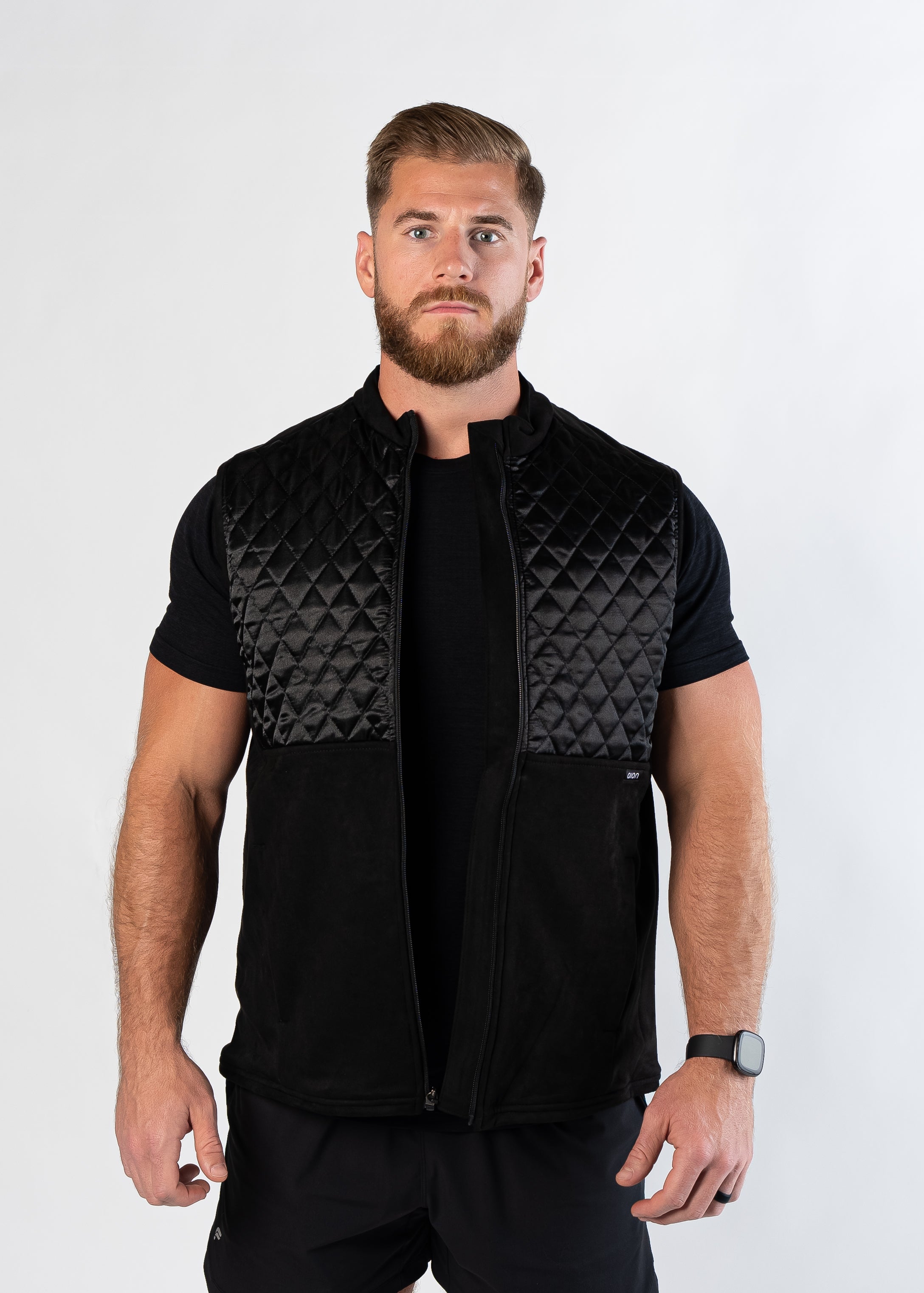 Confident bearded man looking at camera wearing unzipped Aion Boardroom Recovery Vest in black