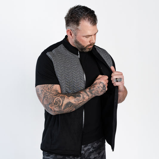 Tattooed man examining zippers on Aion Boardroom Recovery Vest in Chevron Gray
