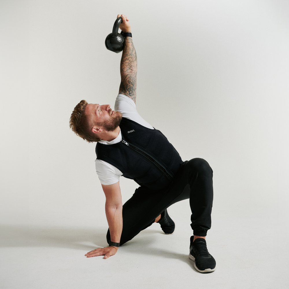 Man lifting dumbbells while wearing Aion men’s weighted workout vest | Model: Height: 5'11" Wearing: Size L