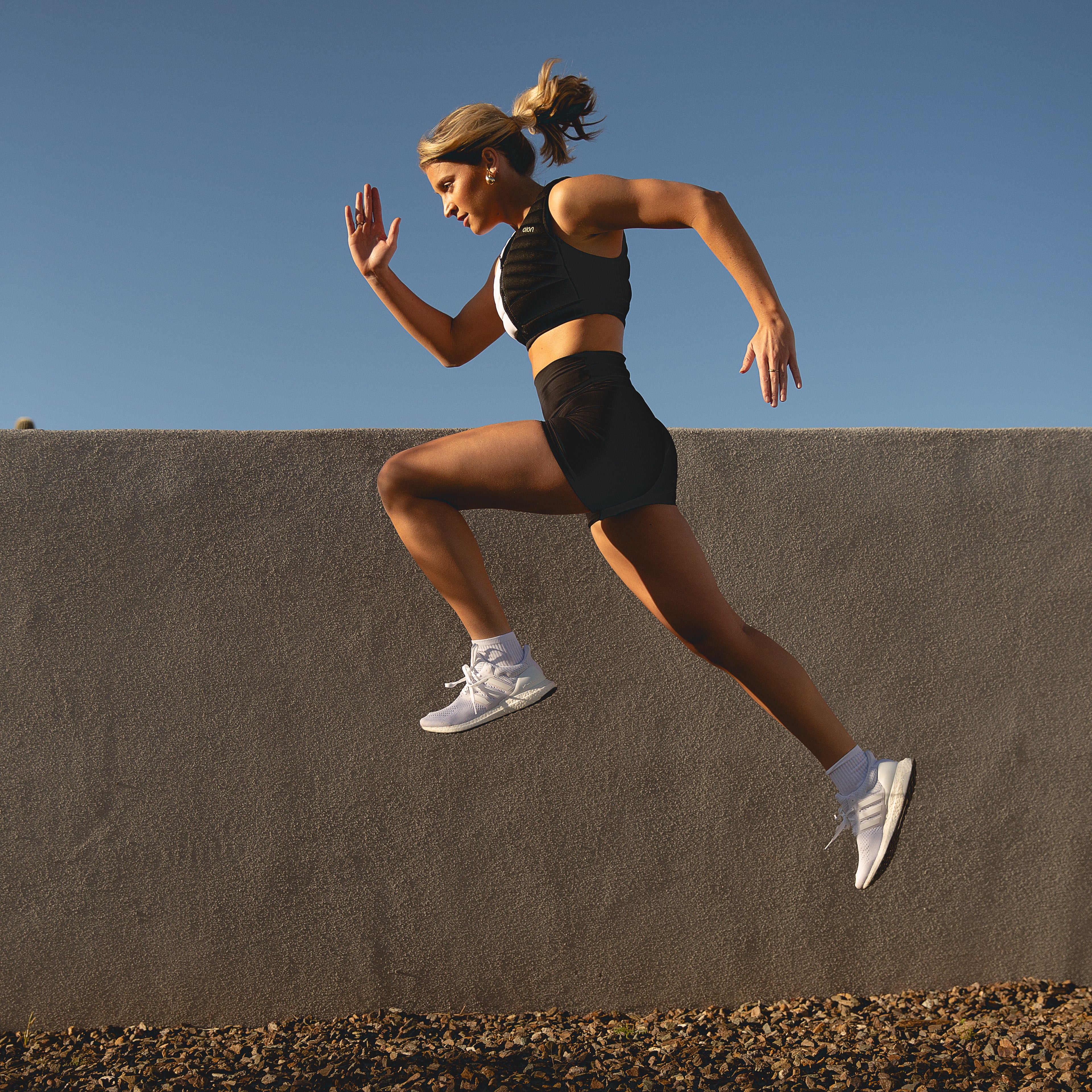 Woman running outdoors wearing Aion’s black and white workout crop vest | Model: Height: 5'8" Wearing: Size XS