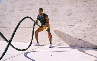 Very muscular man wearing Aion men's weighted vest while throwing weighted rope