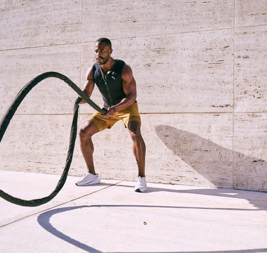 Very muscular man wearing Aion men's weighted vest while throwing weighted rope