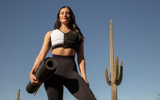 Woman holding a yoga mat wearing Aion women's workout crop vest