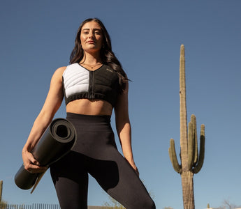 Woman holding a yoga mat wearing Aion women's workout crop vest