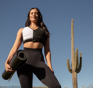 Woman holding a yoga mat wearing Aion women's workout crop vest