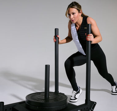 Aion Ambassador and world-renowned fitness cover model Paige Hathaway wearing an Aion weighted vest pushing a weighted sled