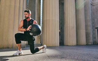 fit man doing walking lunges with a large weighted medicine ball wearing the Aion men's weighted vest