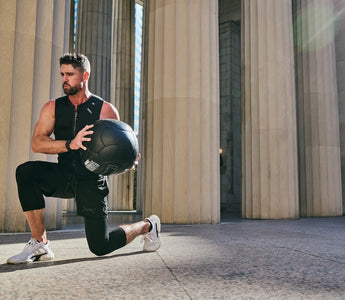 fit man doing walking lunges with a large weighted medicine ball wearing the Aion men's weighted vest