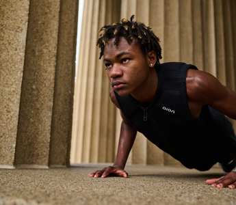 Athlete wearing a black Aion weighted vest performing push-ups outdoors between stone columns