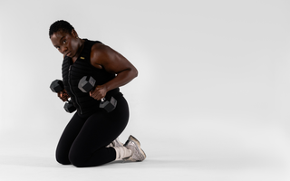 Woman performing strength training with dumbbells while wearing an Aion weighted vest, showcasing functional fitness, resistance training, muscle endurance, and high-performance workouts.