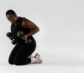 Woman performing strength training with dumbbells while wearing an Aion weighted vest, showcasing functional fitness, resistance training, muscle endurance, and high-performance workouts.