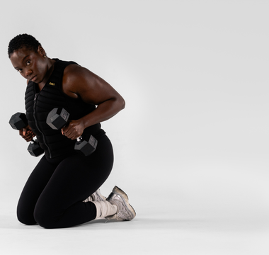 Woman performing strength training with dumbbells while wearing an Aion weighted vest, showcasing functional fitness, resistance training, muscle endurance, and high-performance workouts.