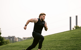 Athletic man sprinting uphill wearing an Aion weighted vest, showcasing high-intensity outdoor training for fat loss, endurance, and strength building.