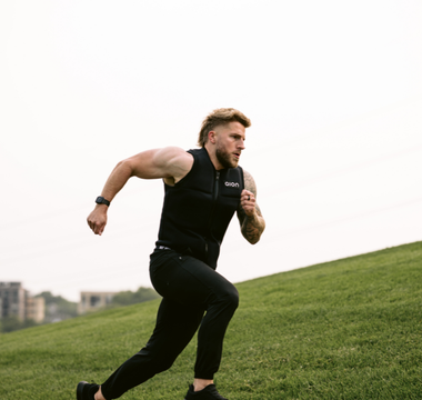 Athletic man sprinting uphill wearing an Aion weighted vest, showcasing high-intensity outdoor training for fat loss, endurance, and strength building.