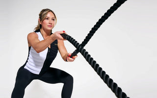 Paige Hathaway World-renowned fitness cover model, entrepreneur, and fitness influencer wearing the Aion women's weighted vest while in a squat position throwing ropes