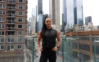 a fit young woman wearing the Aion Women's Weighted Walking Vest at Life Time Fitness Club NYC outdoor patio with NYC skyline in the background