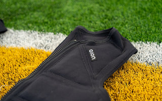 Aion men's weighted vest laying on artificial turf of a football field