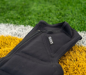 Aion men's weighted vest laying on artificial turf of a football field