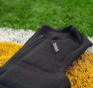 Aion men's weighted vest laying on artificial turf of a football field