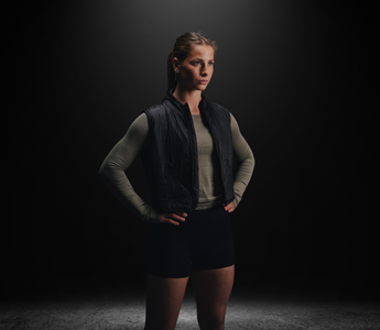 Woman wearing a black Aion weighted walking vest in a studio, highlighting its streamlined fit and everyday performance design