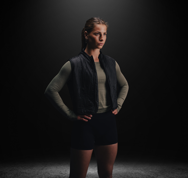 Woman wearing a black Aion weighted walking vest in a studio, highlighting its streamlined fit and everyday performance design
