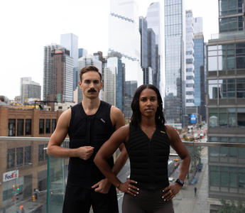 Two athletes wearing Aion weighted vests stand confidently on a city rooftop, showcasing strength, performance, and urban training against a modern skyline backdrop