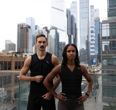 Two athletes wearing Aion weighted vests stand confidently on a city rooftop, showcasing strength, performance, and urban training against a modern skyline backdrop